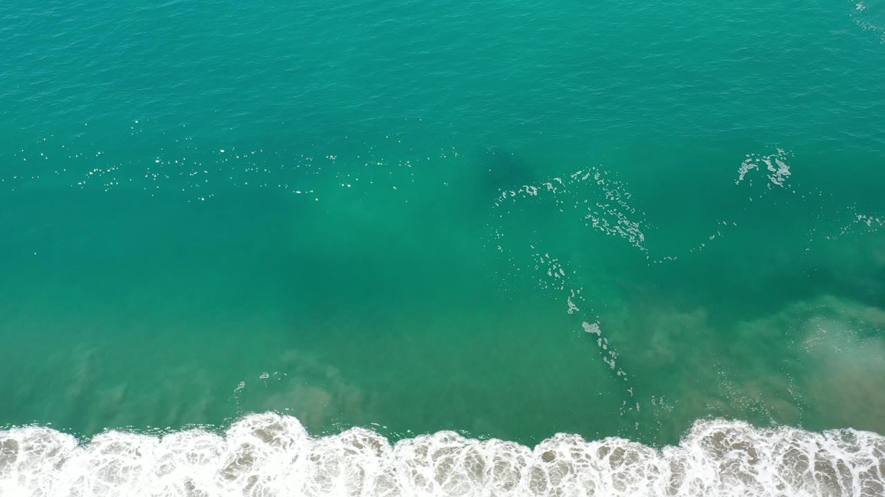 Overhead surf with dark underwater form near the upper water.