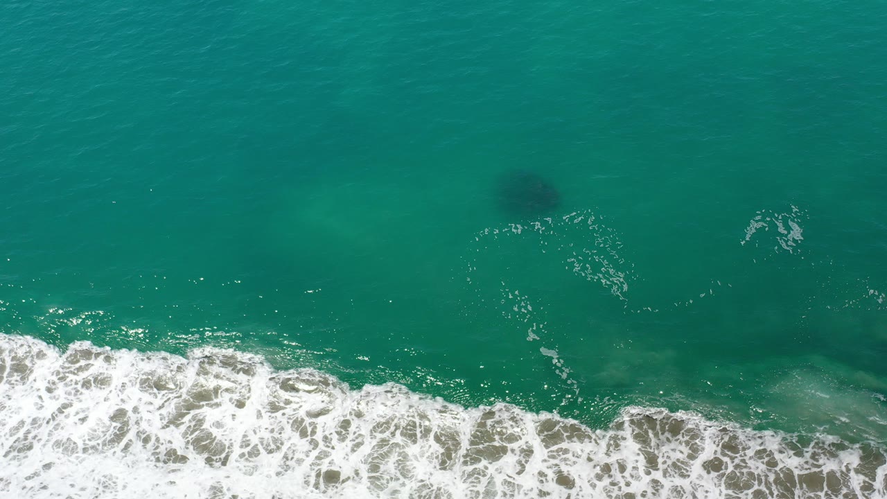 Overhead turquoise ocean with white surf along the lower edge.