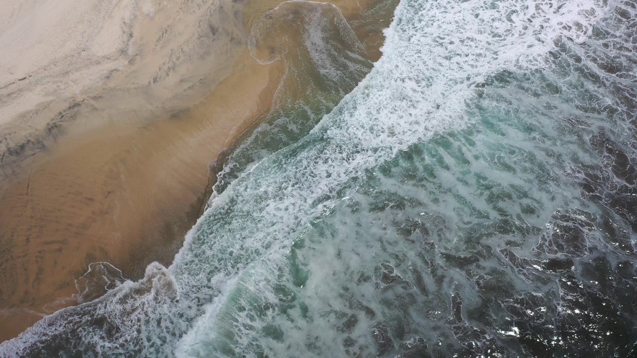 Breaking surf curling along sandy beach