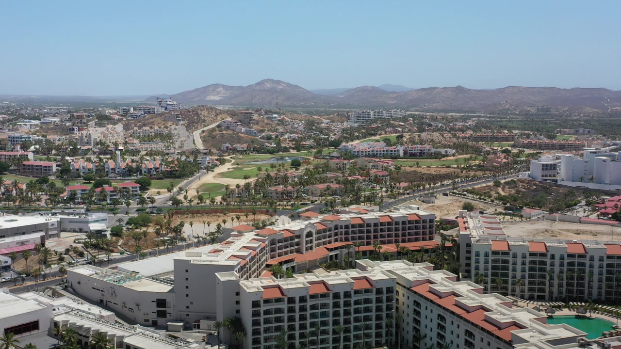 Wide elevated city view with resorts, neighborhoods, golf-like greens, and mountains