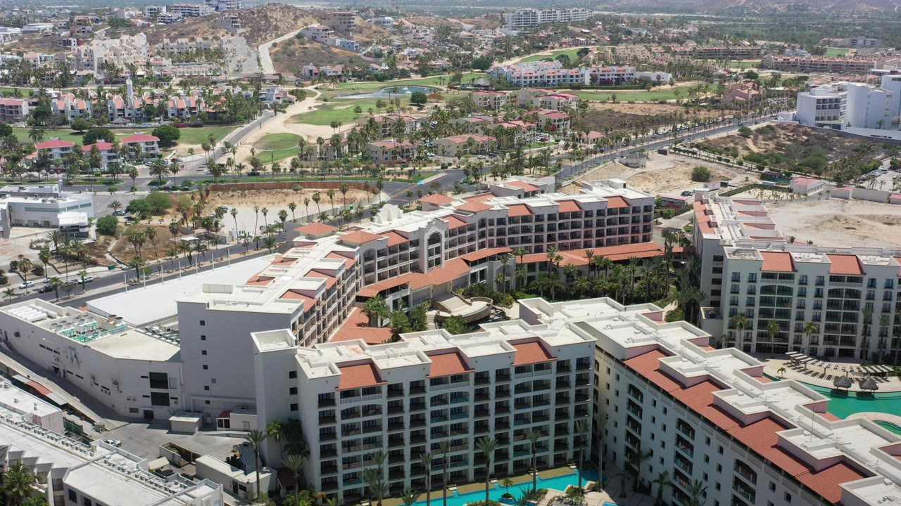 Aerial view of a white resort complex with red roofs and pools.