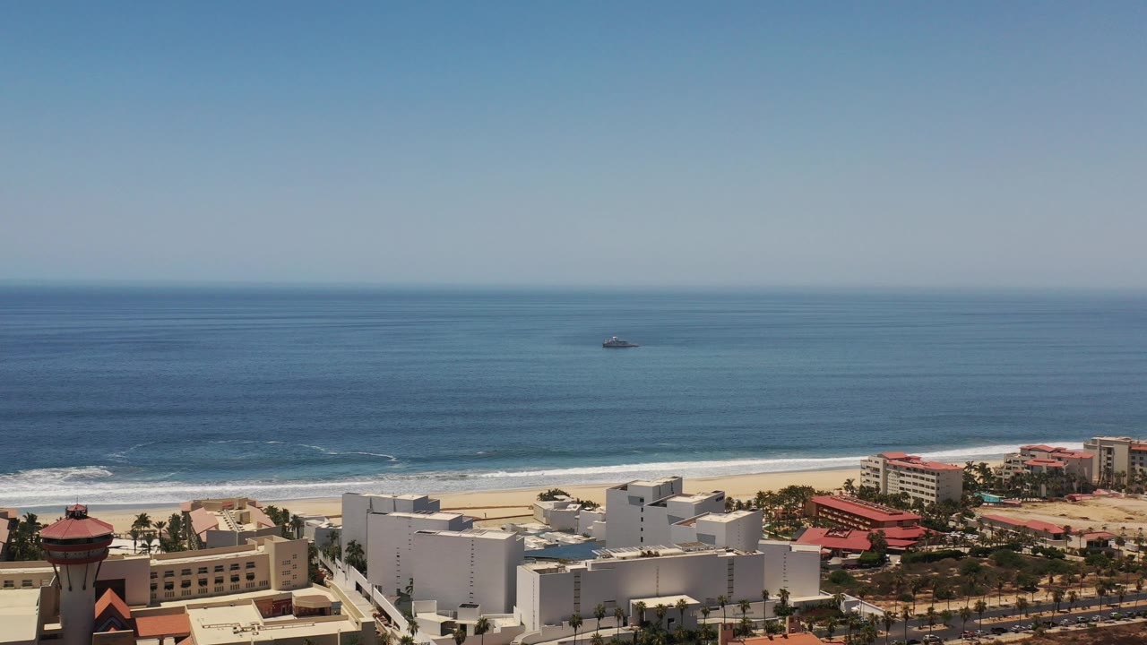 Beachfront resort area beside surf and open ocean.
