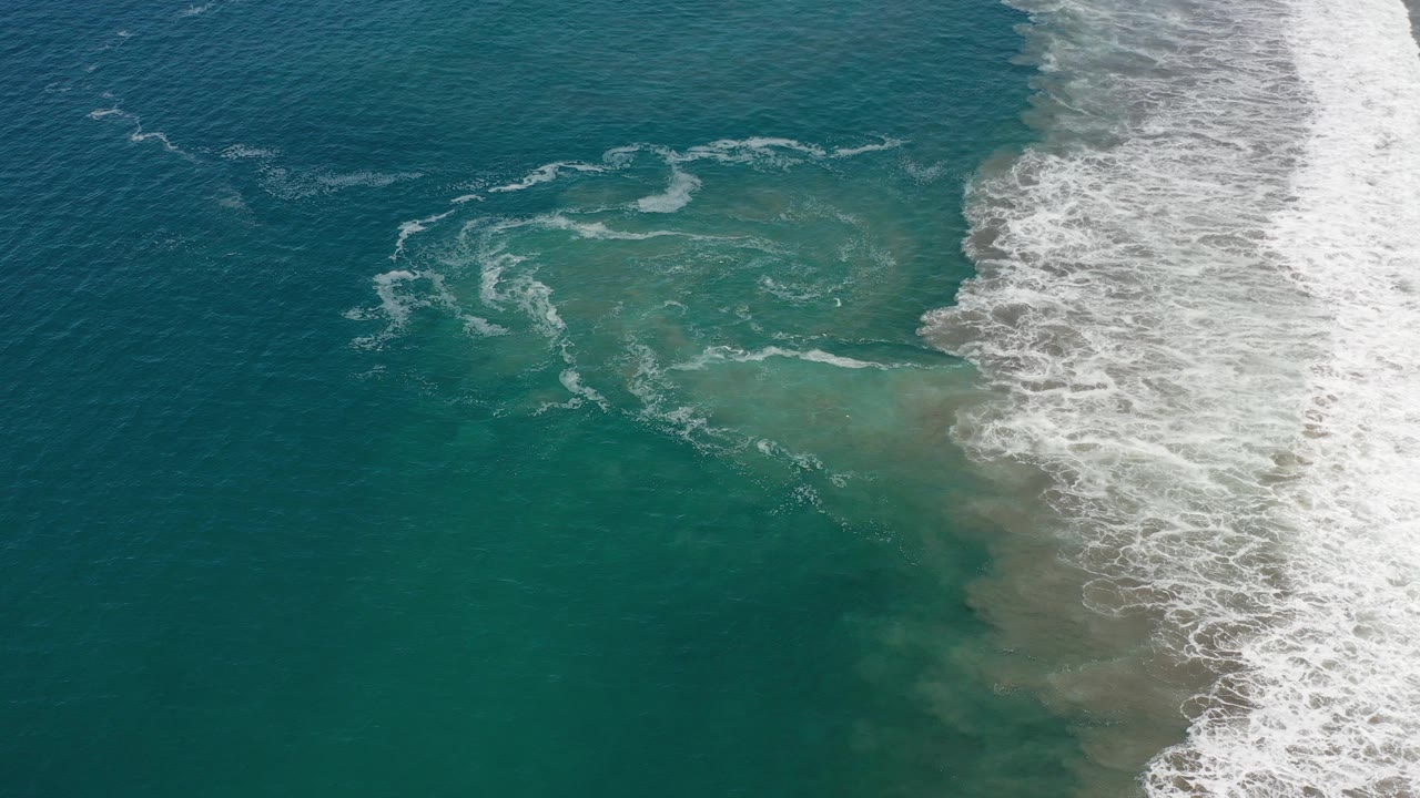 Opening frame of Los Cabos ocean water with a white surf band entering from the right and no visible people.