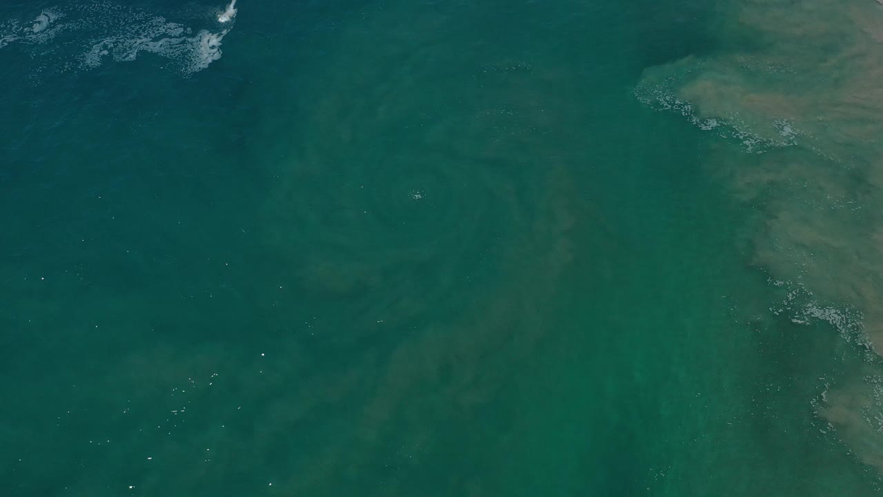 Overhead teal water with tan mass along the right side.