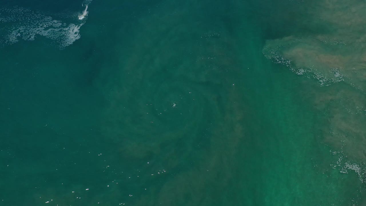 Teal-green water with a pale rocky-looking shape along the right side.
