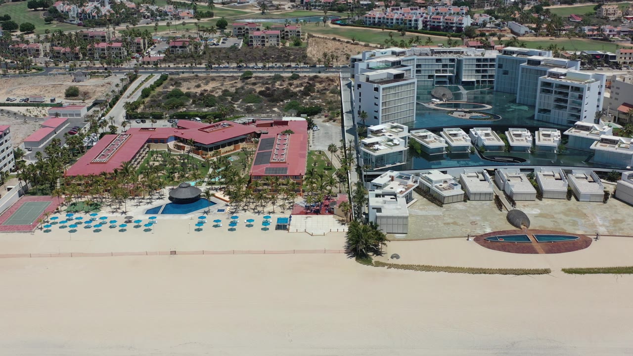 Aerial view of a sandy beach beside beachfront buildings and streets.