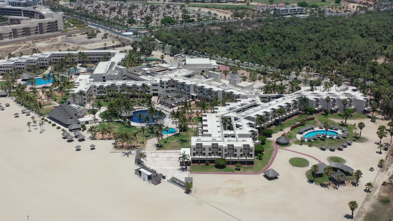 Aerial view of a beachfront hotel with pools and trees