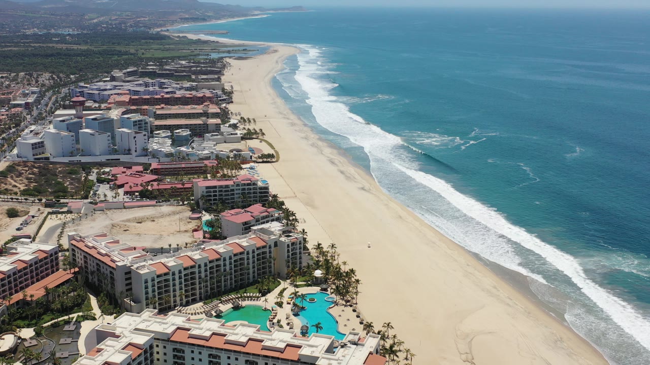 Aerial view of beachfront resorts beside a wide sand beach and blue ocean