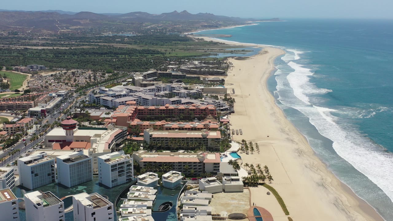 Aerial view of beach, ocean surf, hotels, and inland hills