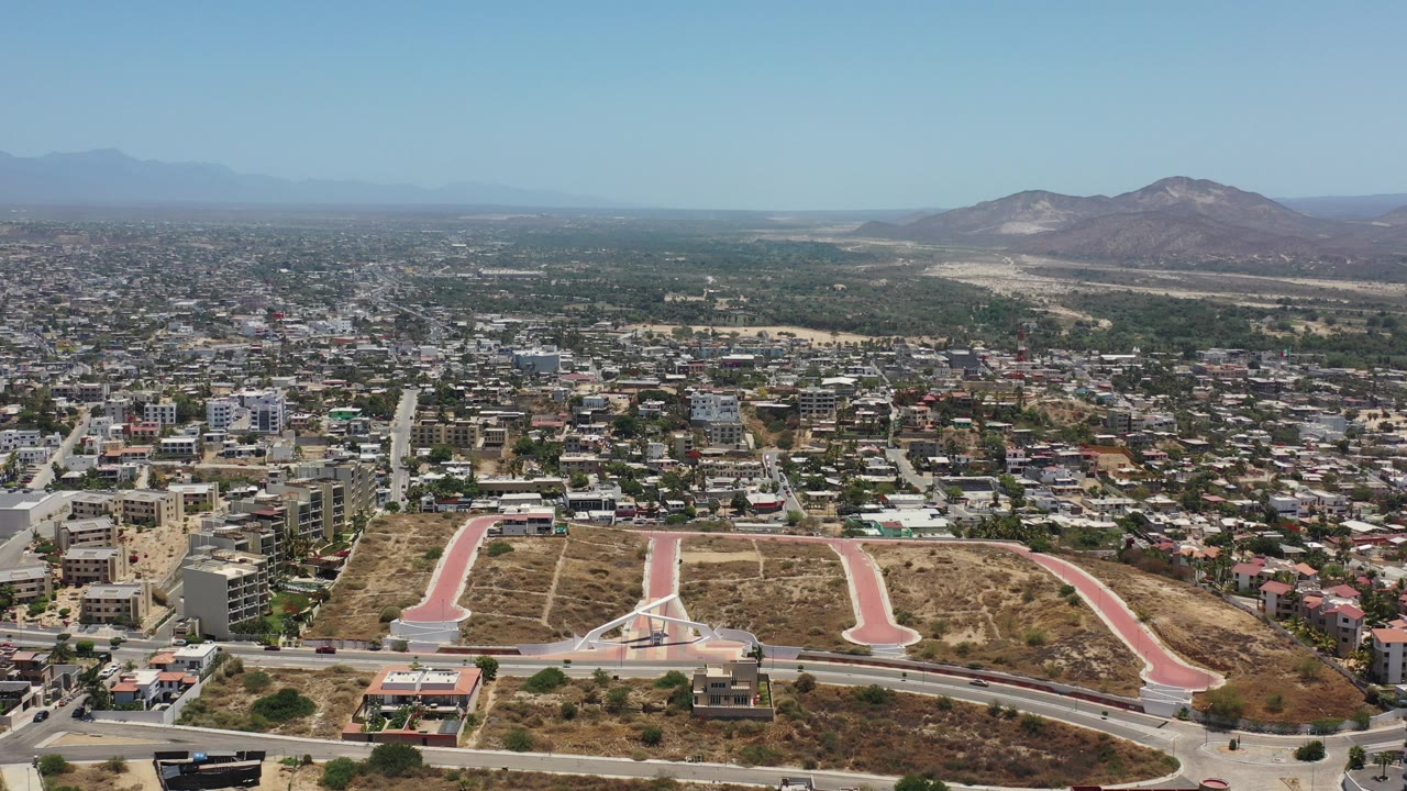 Aerial view of a city with dry lots, roads, and distant mountains.