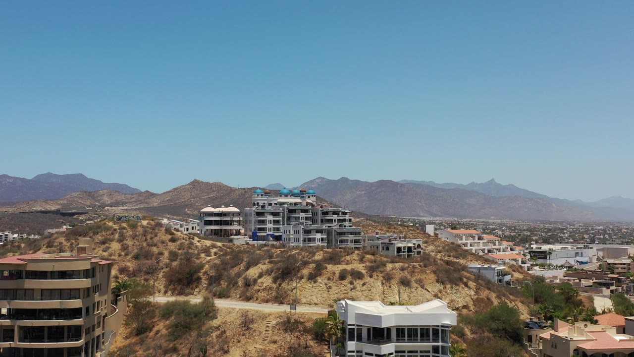 Dry hillside city view with buildings and distant mountains