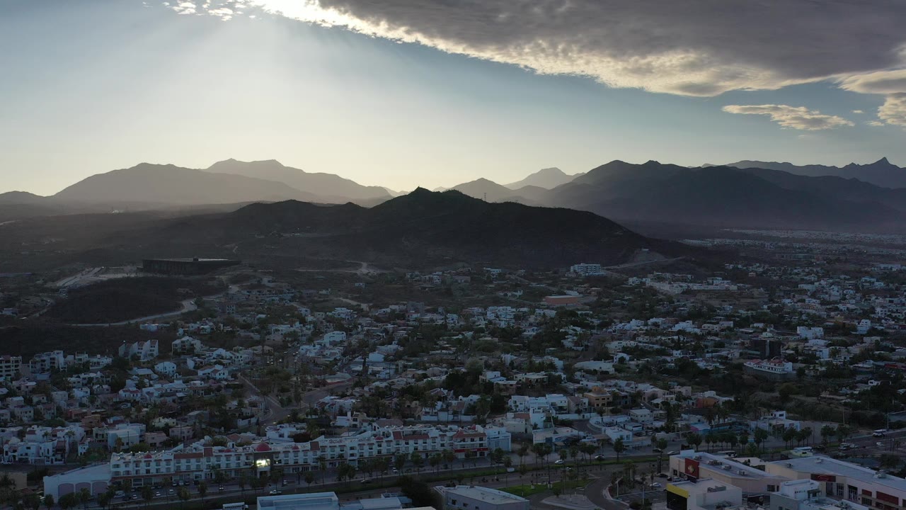 Wide city view with mountain silhouettes and a thick cloud edge across the upper sky.