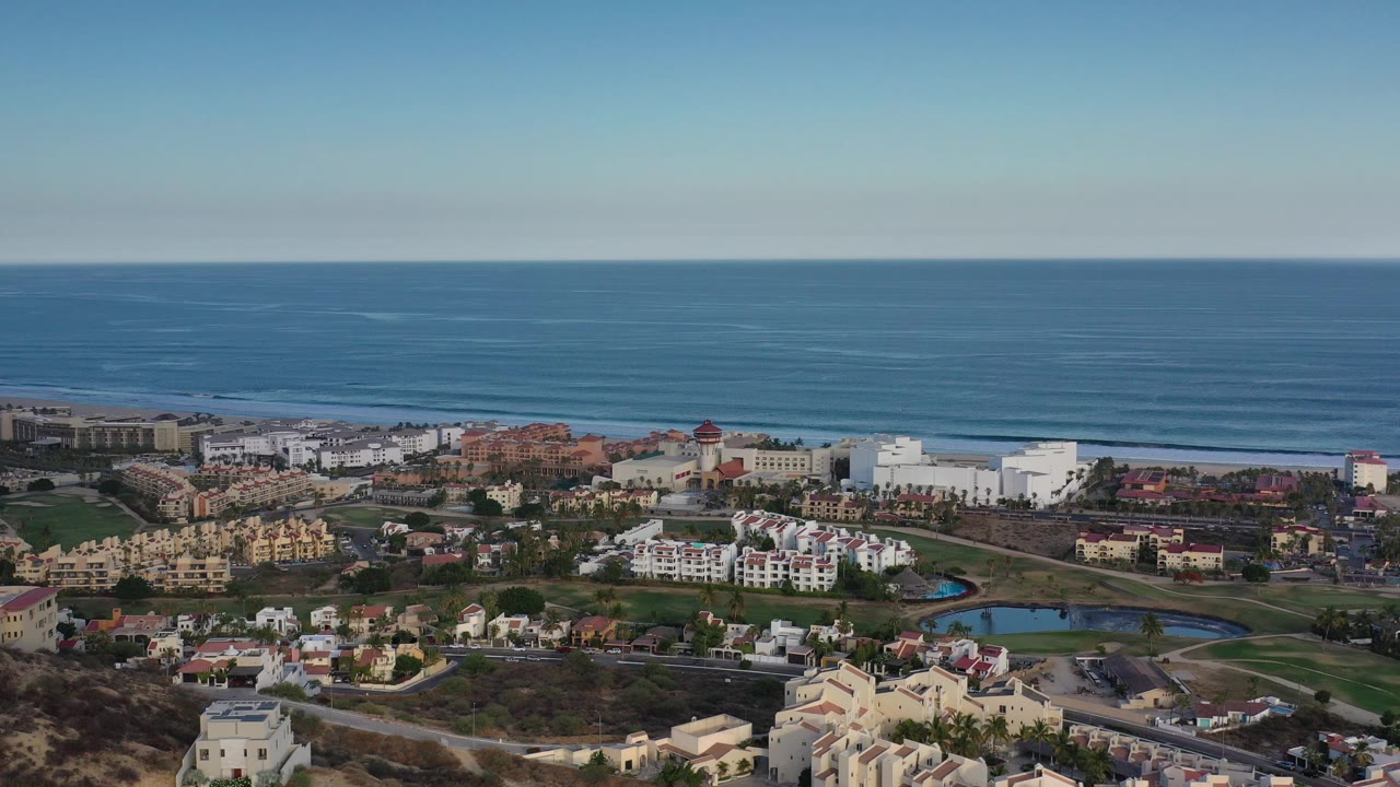 Aerial view of ocean beyond a coastal city with buildings and roads