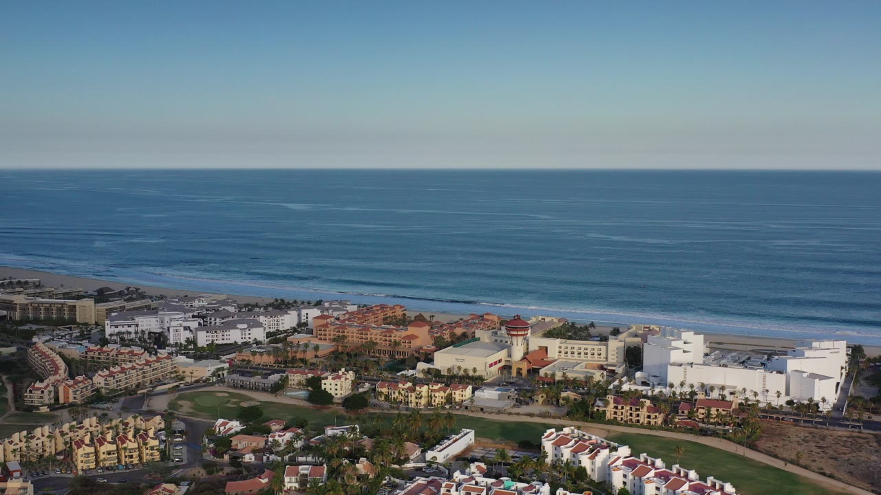 Aerial view of coastal buildings beside a calm blue ocean.