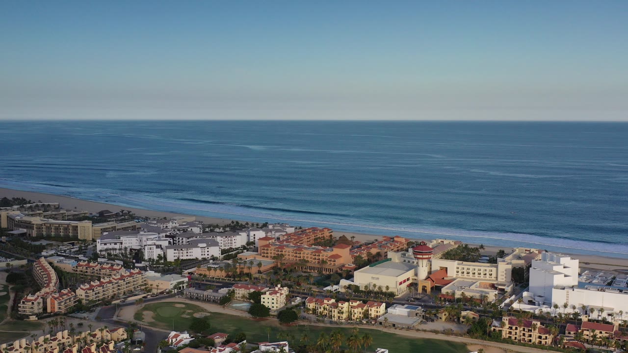 Aerial view of blue ocean, beach, and hotel buildings.