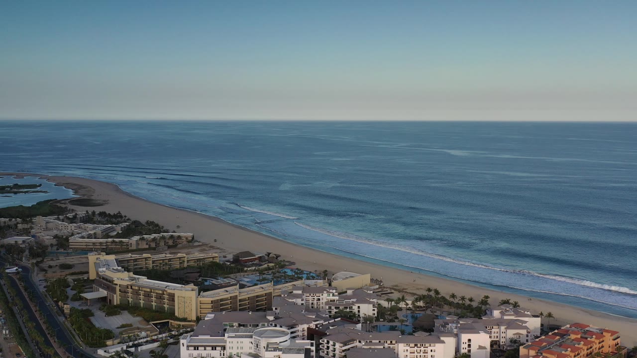 Drone-like view of a beach resort area and ocean surf.