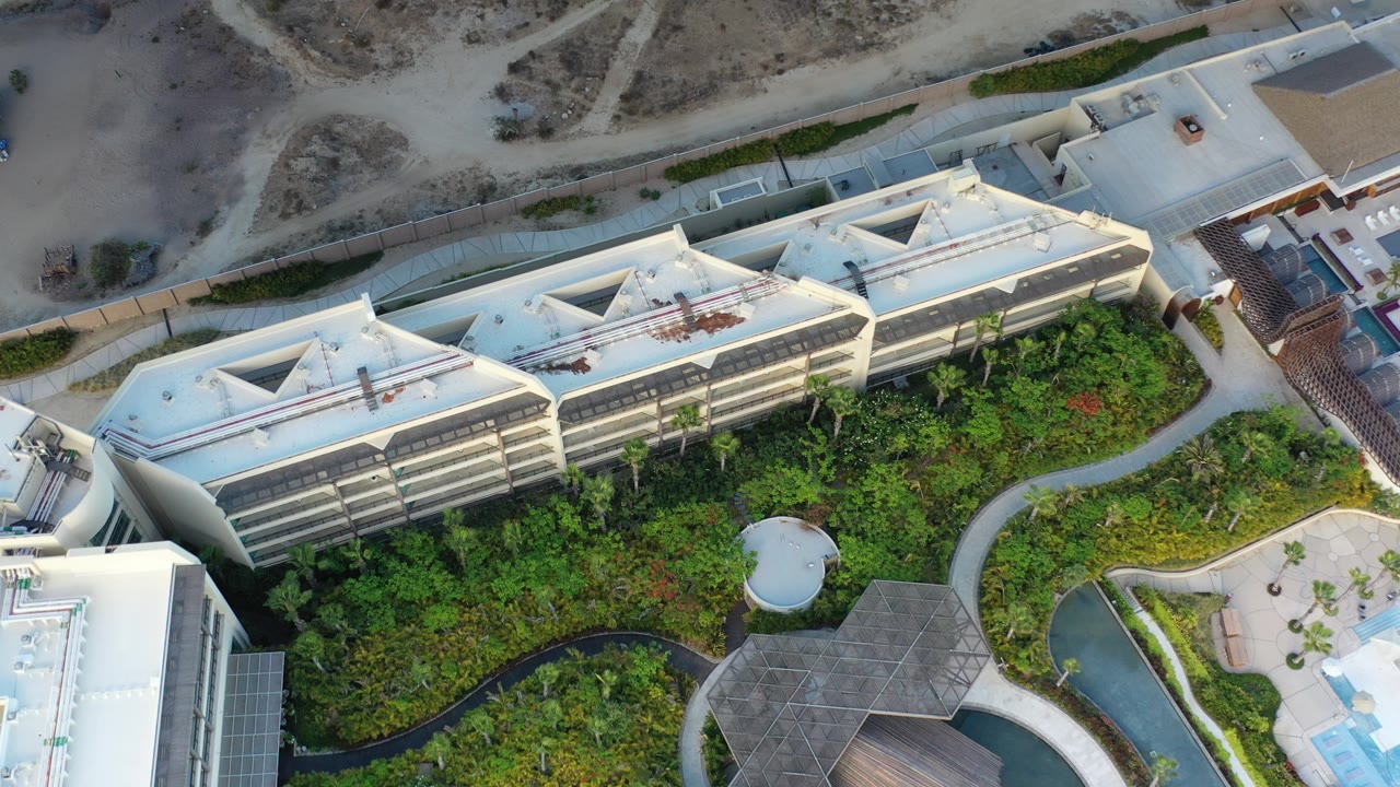 Overhead view of a white condominium and green landscaped grounds.