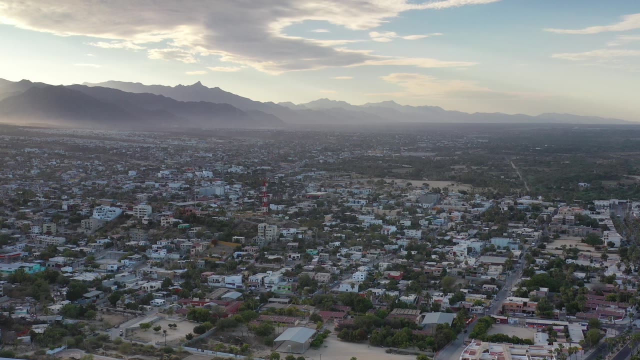 Residential blocks, open lots, and distant mountains seen from above.