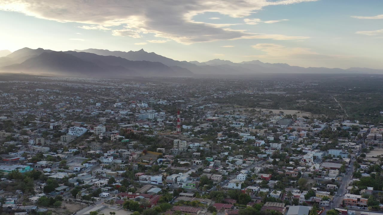 Aerial city view below mountains and bright sky.