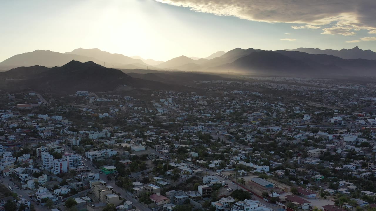 City grid and mountain range under a bright hazy sky.