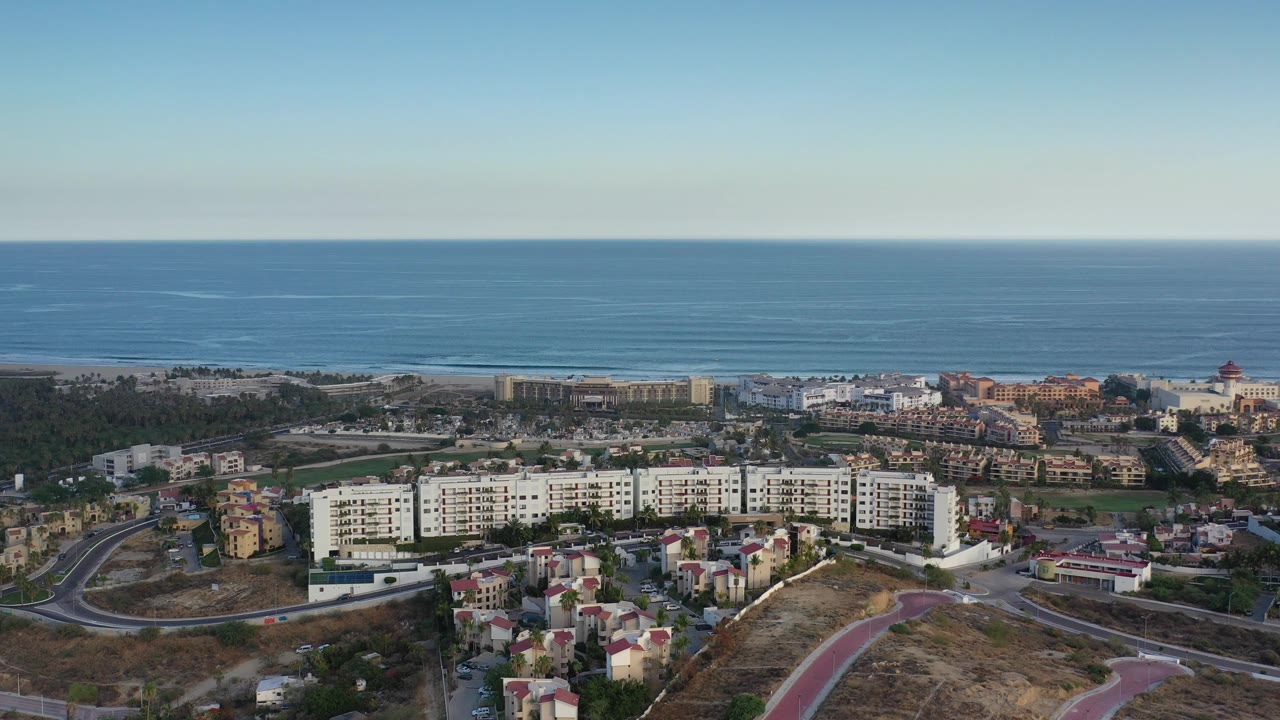 Coastal neighborhood and condos beneath a wide blue ocean horizon.