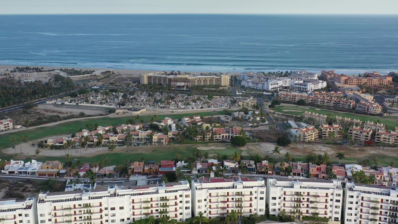 Aerial view of coastal homes, apartment buildings, open lots, and ocean.