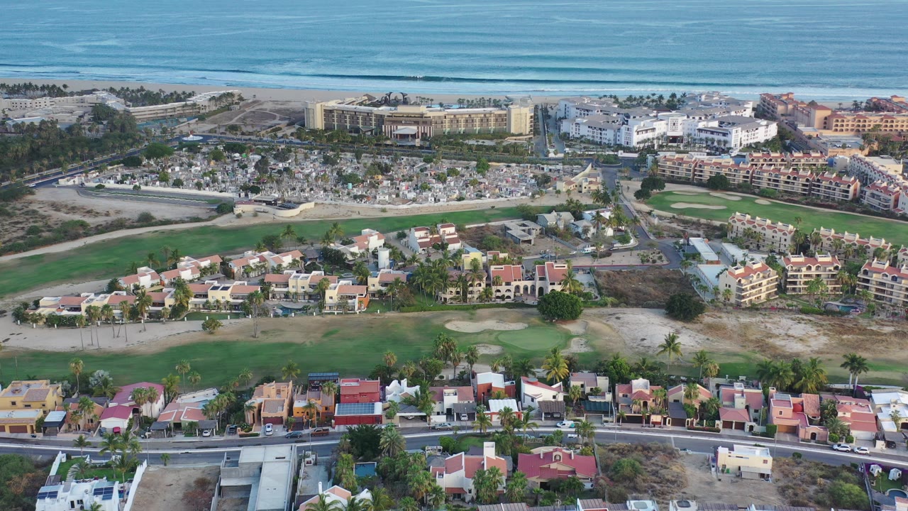 Aerial view of coastal homes, resort buildings, beach, and ocean.