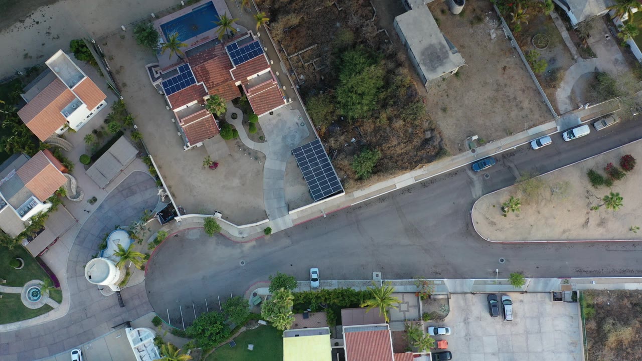 Overhead view of a residential intersection with houses, cars, and dry lots.