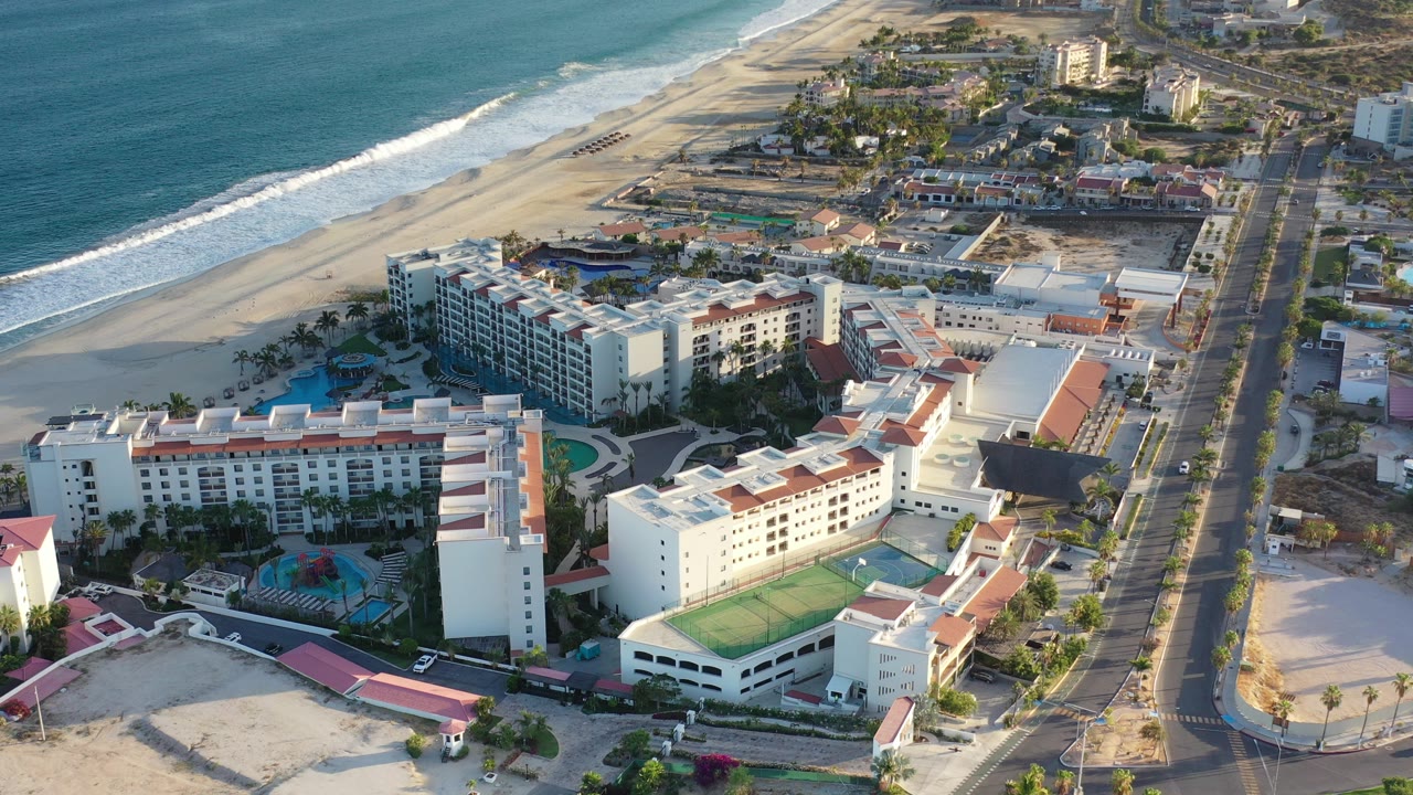 Aerial view of a large beachfront resort beside surf and sand.