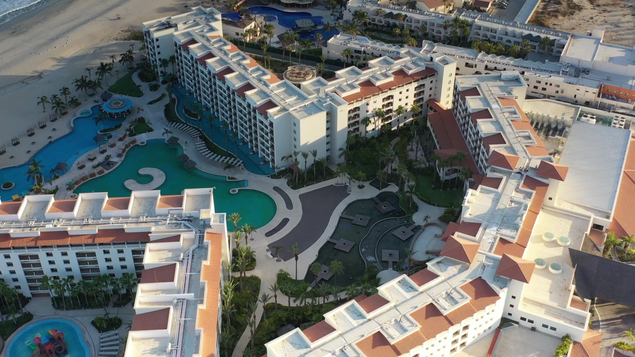Aerial view of resort buildings and turquoise pools near a beach