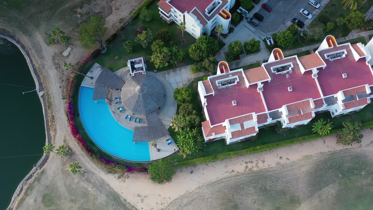 Overhead view of red-roofed homes beside a curved blue pool and waterway.