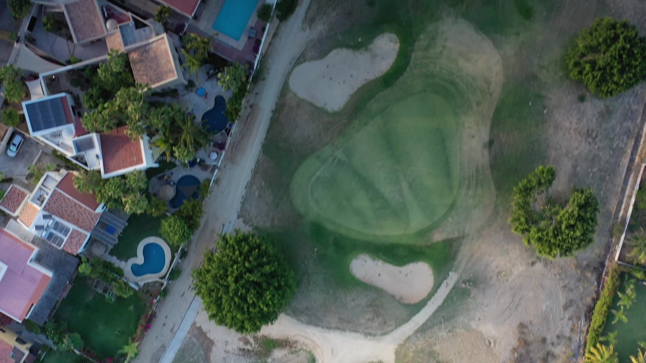 Overhead golf green beside homes and pools