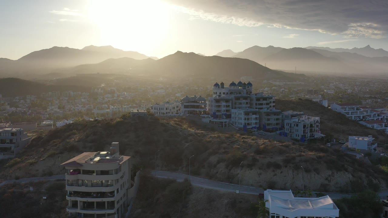 Backlit hillside buildings above a hazy valley and mountains.
