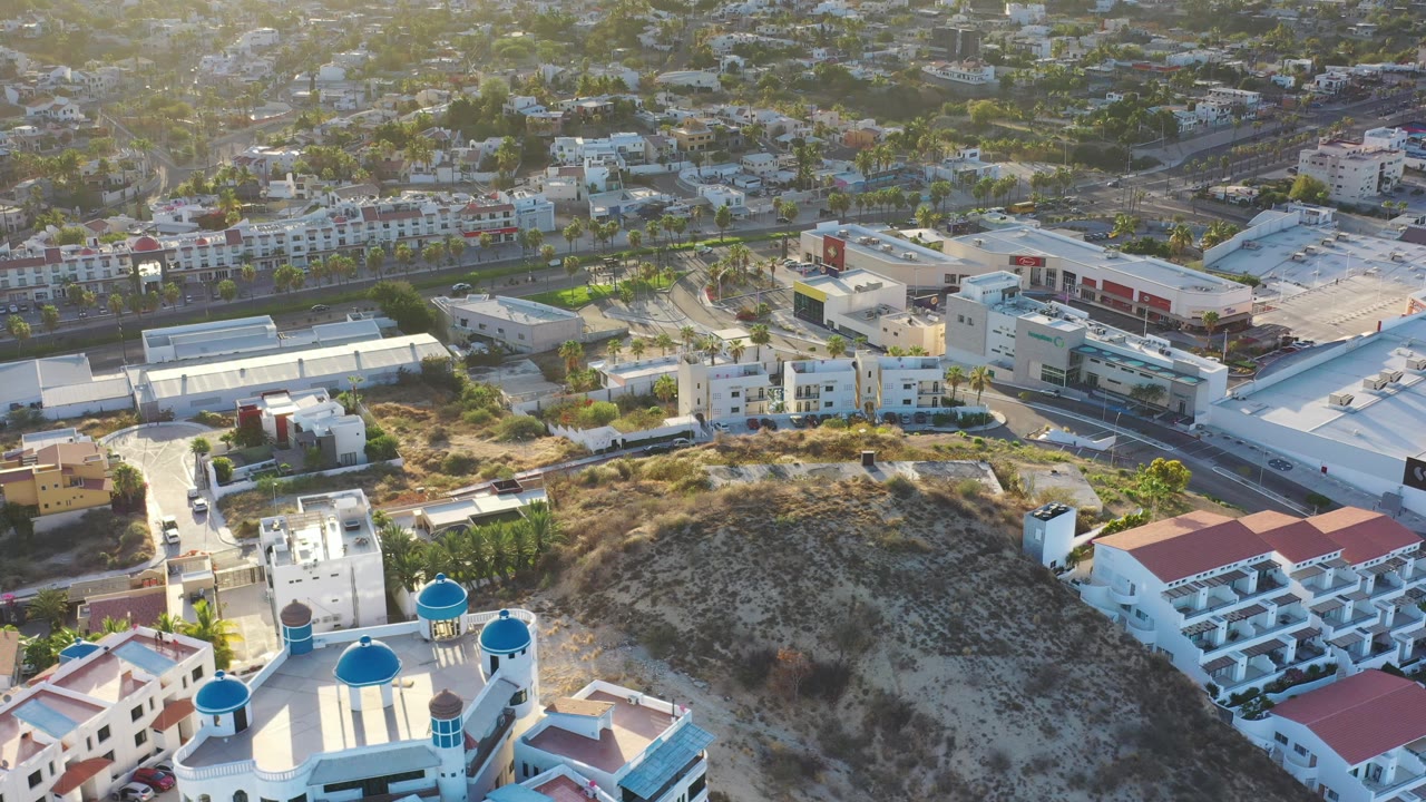 Elevated view of a scrub-covered hill with roads and low-rise buildings beyond it.