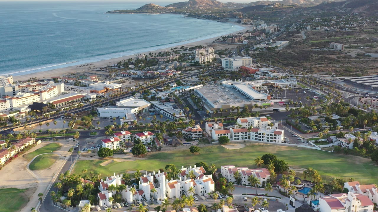 Aerial view of beach, coastal buildings, golf course, and ocean
