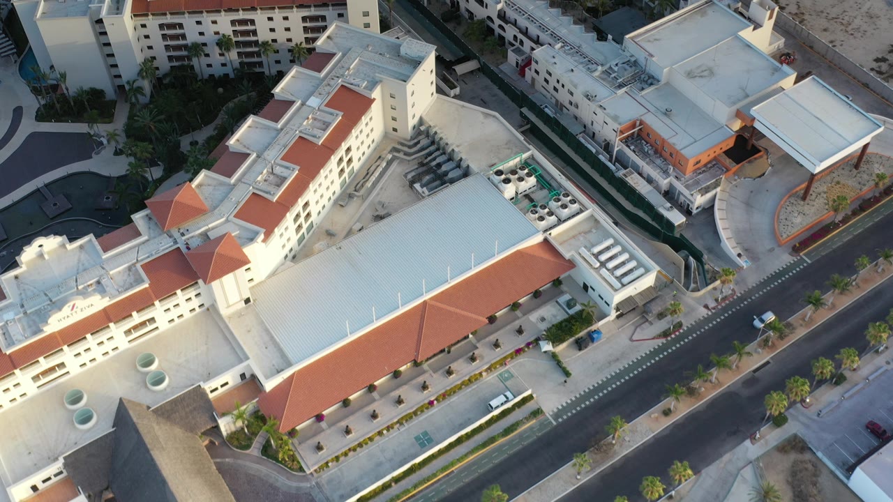 Drone-style view of white buildings, red roofs, and a curving street.