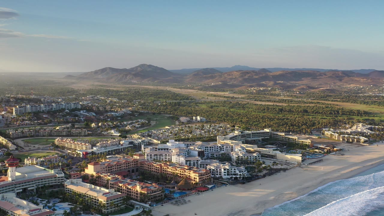 Aerial view of beachside buildings with mountains beyond.