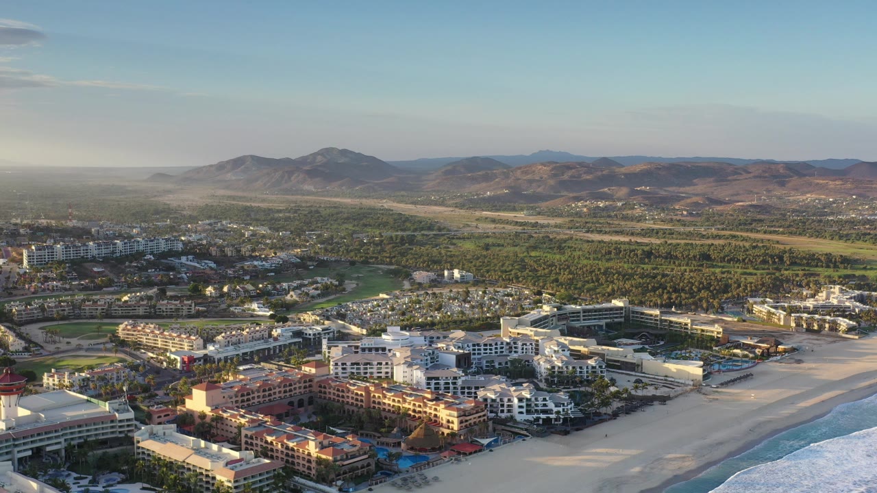 High view of coastal development, beach, surf, and brown hills.