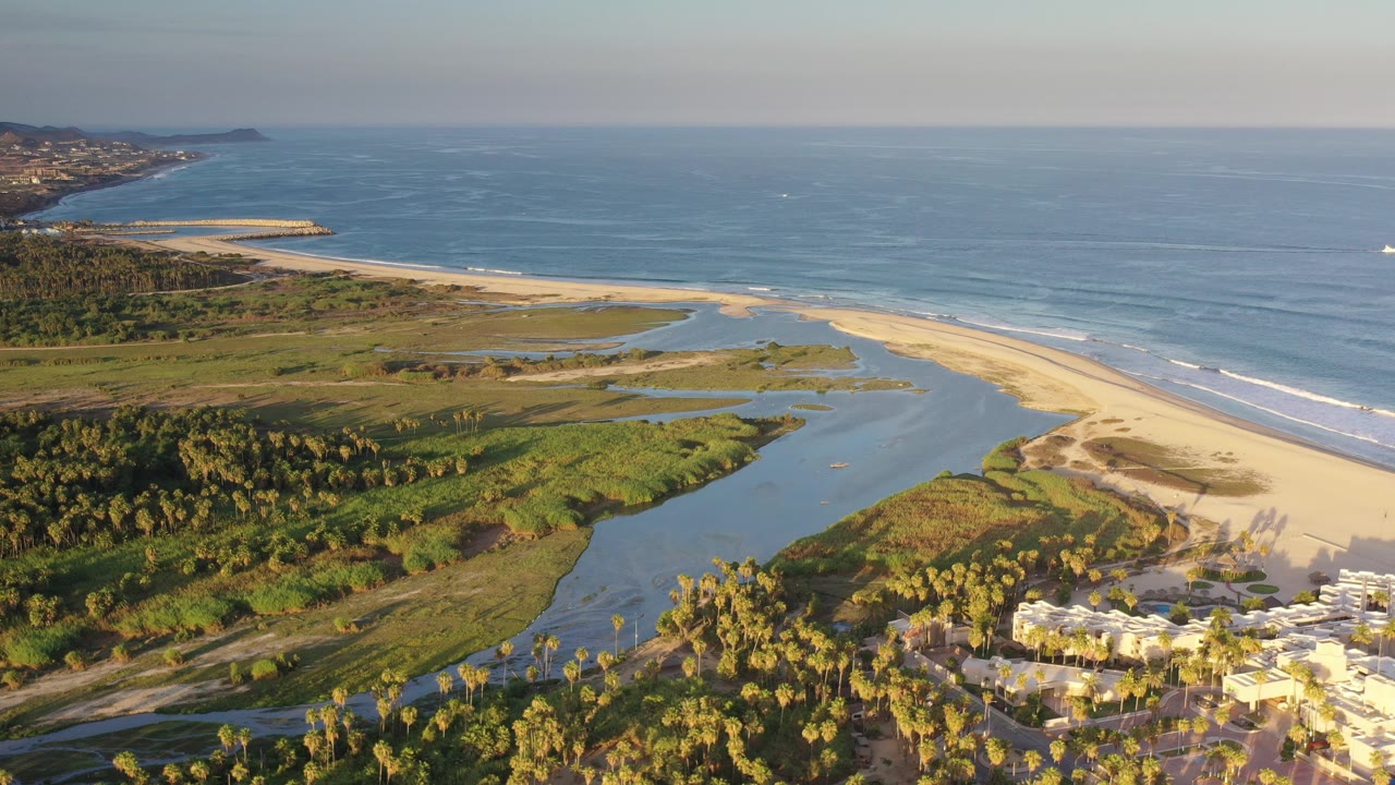Aerial coastline with ocean, beach, lagoon, palms, and buildings