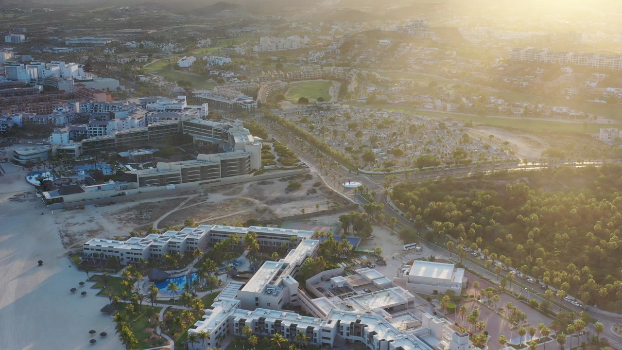 Aerial view of resort hotels, pools, roads, and trees in bright haze.