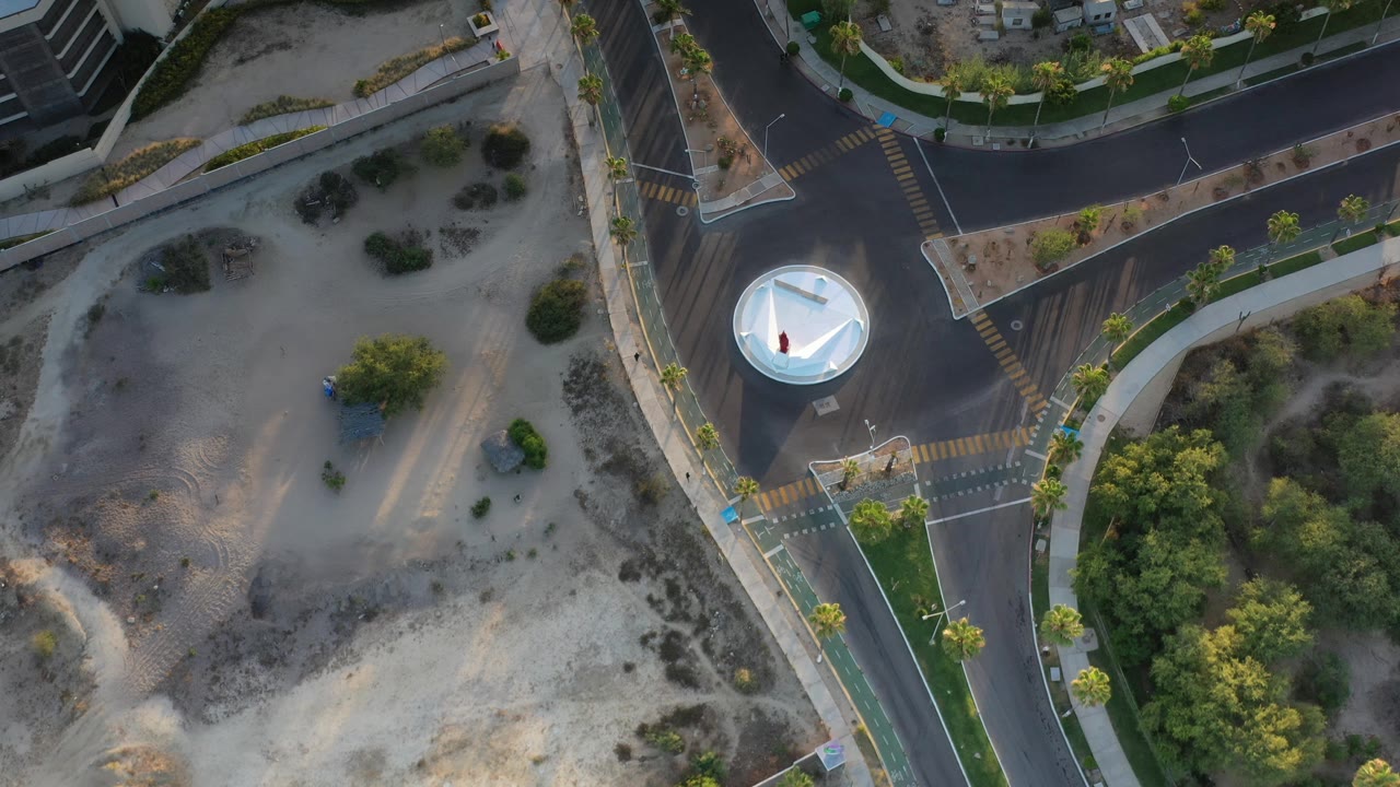Top-down road junction bordered by sandy ground and trees