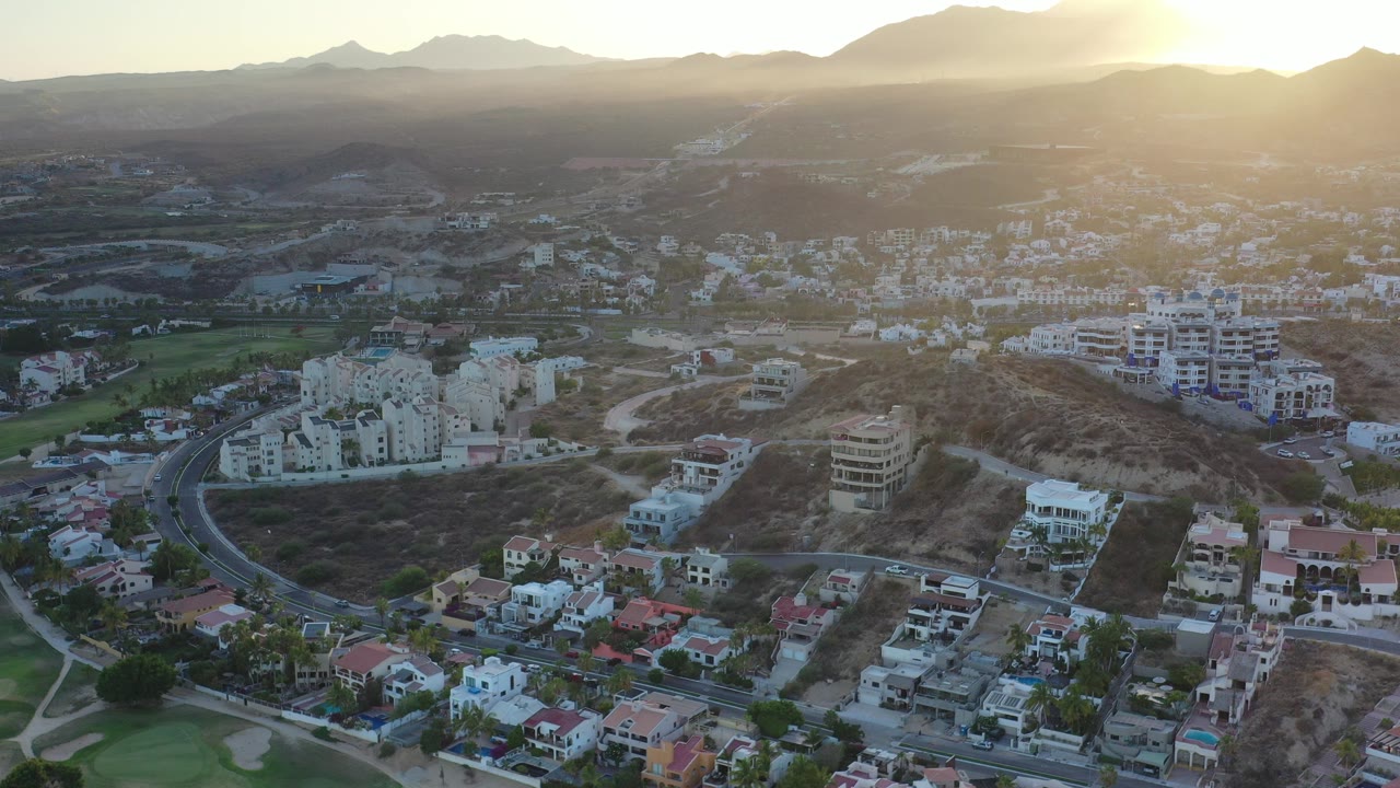 Aerial view of hillside homes and roads at sunset.