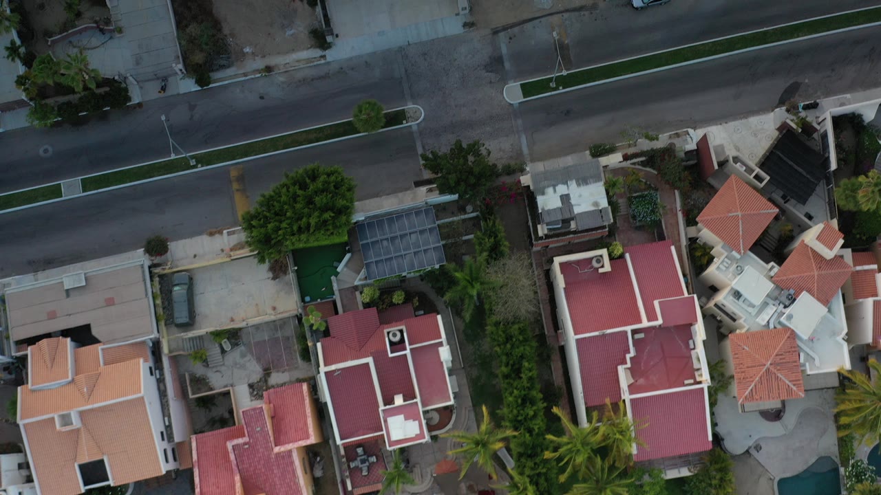 Overhead view of a residential street with red-roofed homes and trees.