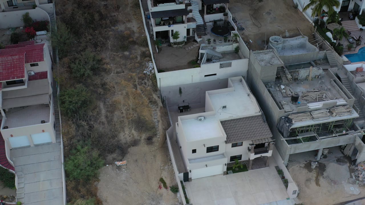 Top-down aerial view of homes beside dry hillside and construction area.