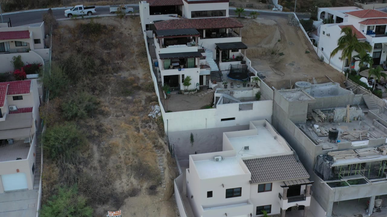 Elevated view of hillside houses beside a dry slope and road.