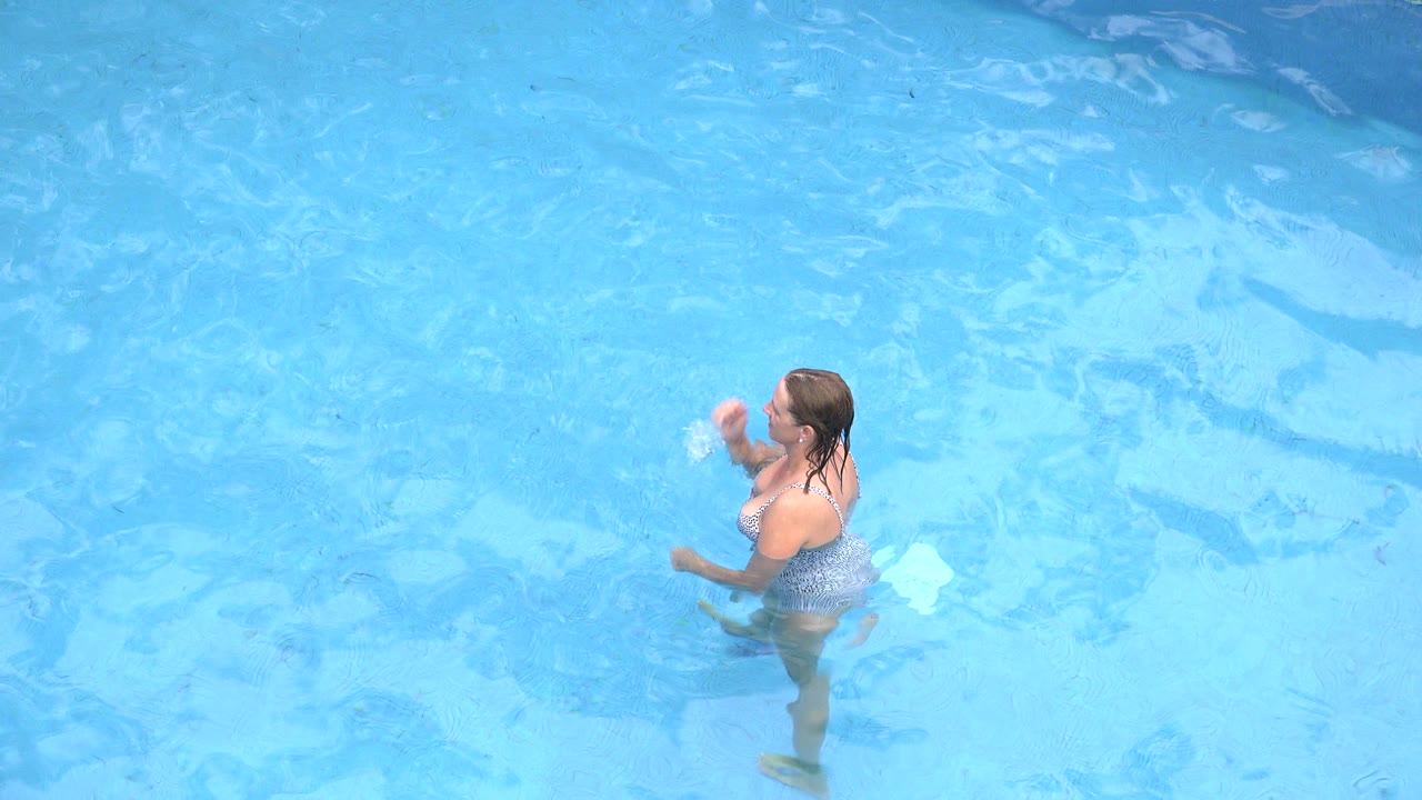 In Los Cabos, Mexico, the woman remains waist-deep in the pool as her raised hand nears her mouth and the water reflections spread across the frame.