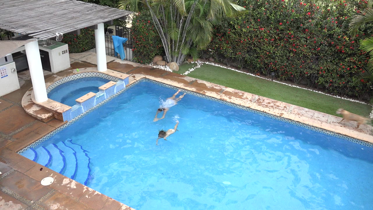 Two swimmers in a blue resort pool viewed from above.