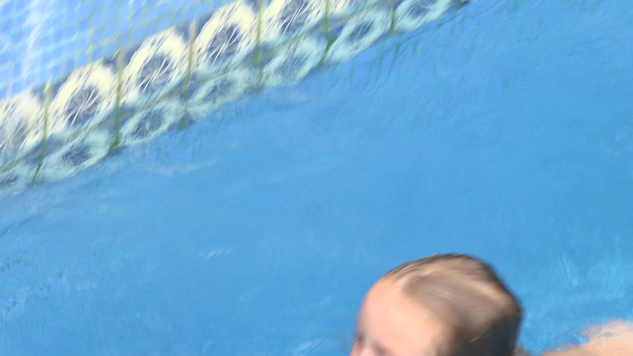 Child partly visible in blue pool water near the top edge.