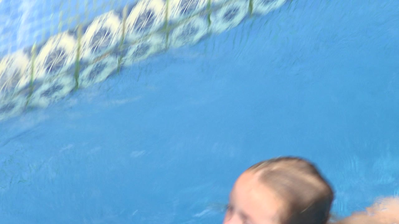 The child remains partly cropped at the bottom of the frame while pale reflections and ripples spread across the blue pool water in Los Cabos, Mexico.