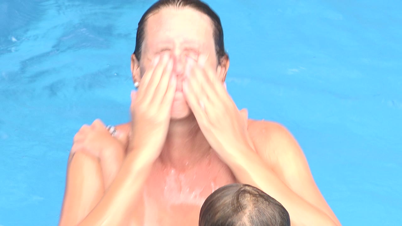 One second into the Los Cabos clip, the mother remains close to the child with both palms over her face as bright blue pool water fills the whole background.